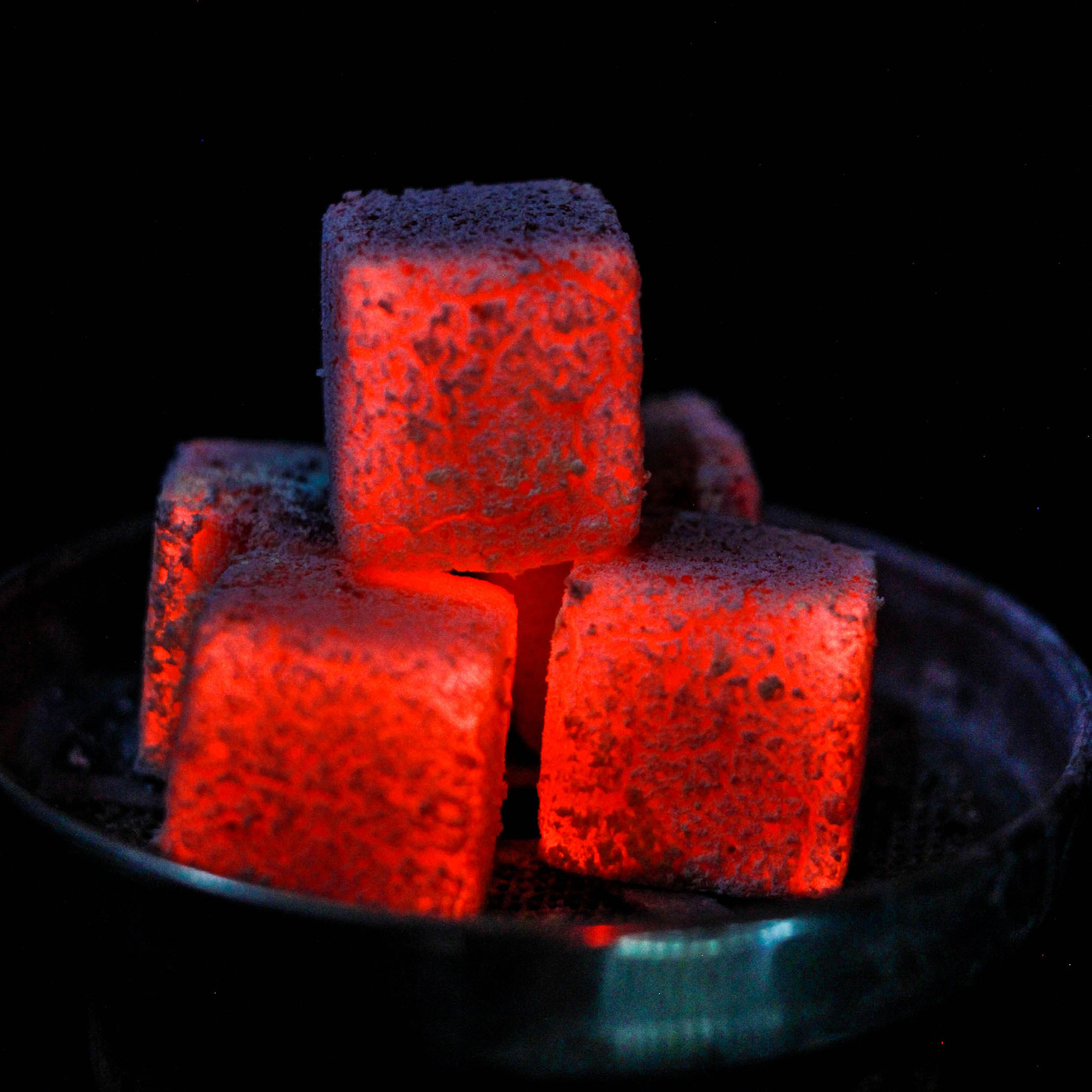 Top view smoldering coals with fire drops in steel flask on dark Top view smoldering coals with fire drops in steel flask on dark background