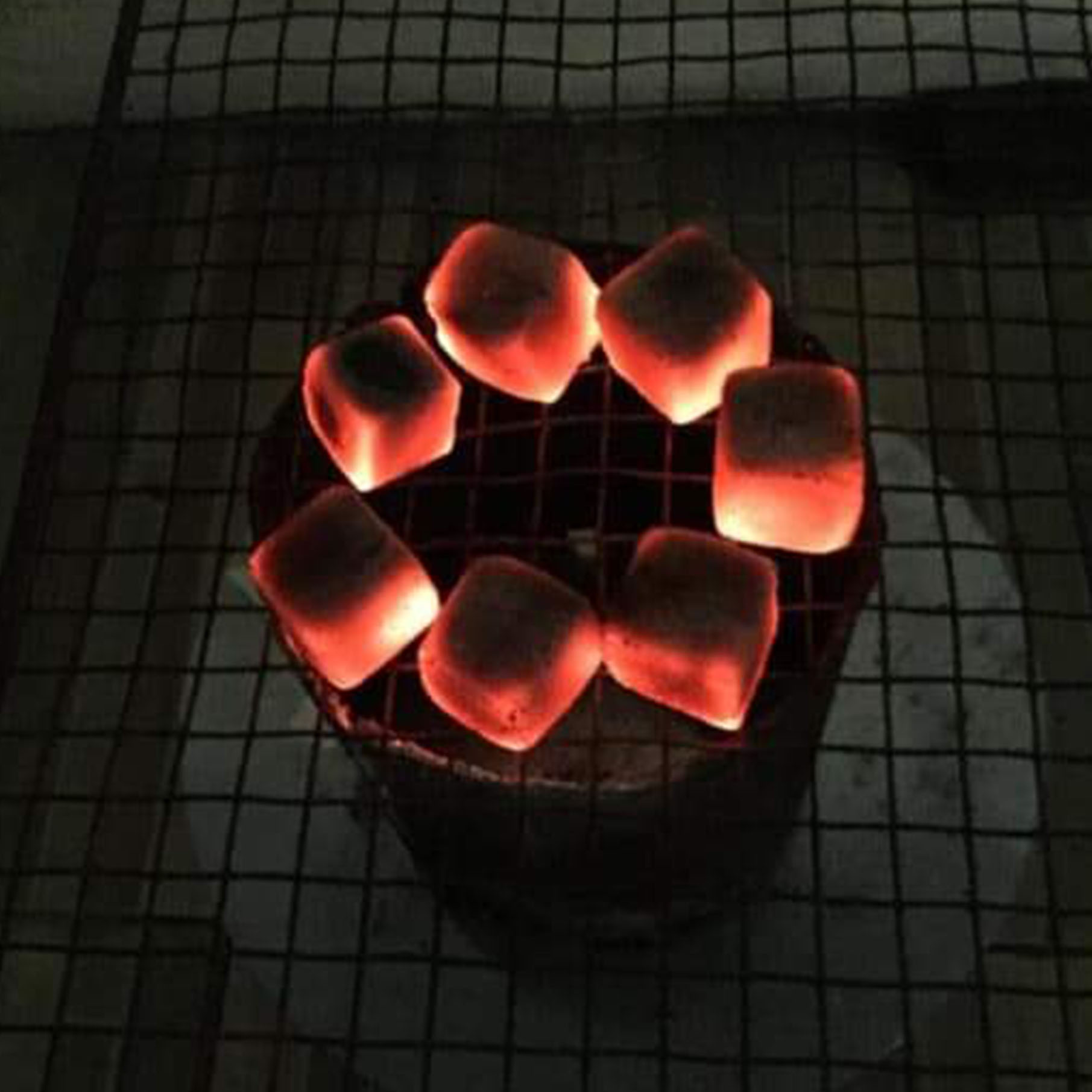 Top view smoldering coals with fire drops in steel flask on dark Top view smoldering coals with fire drops in steel flask on dark background